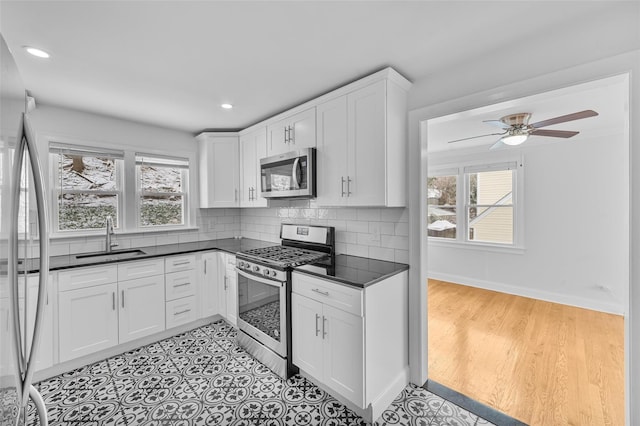 kitchen featuring appliances with stainless steel finishes, white cabinetry, a healthy amount of sunlight, and sink