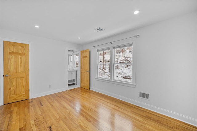 unfurnished bedroom featuring ensuite bathroom and light hardwood / wood-style floors