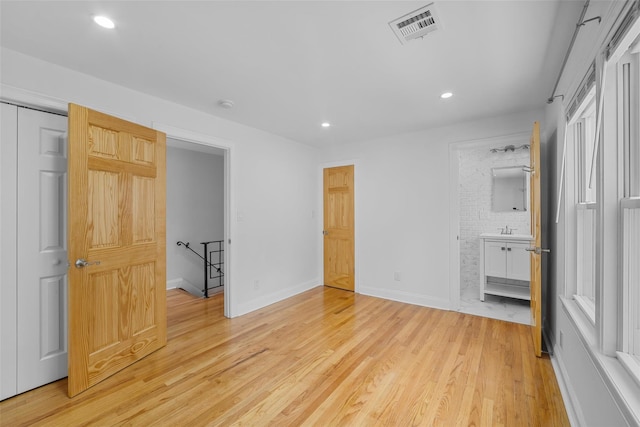 bedroom featuring light wood-type flooring and ensuite bath