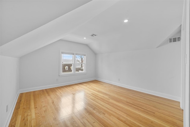 additional living space with light hardwood / wood-style floors and vaulted ceiling