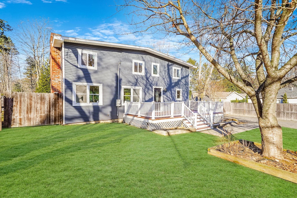 rear view of property featuring a yard and a wooden deck