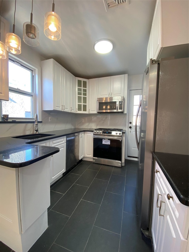 kitchen featuring sink, stainless steel appliances, pendant lighting, white cabinets, and dark tile patterned flooring