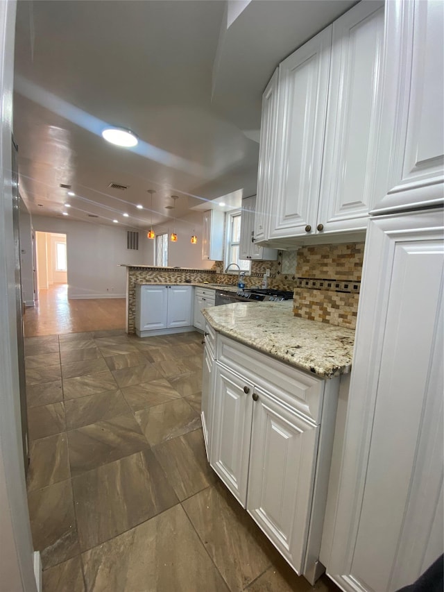 kitchen featuring tasteful backsplash, kitchen peninsula, light stone countertops, and white cabinets