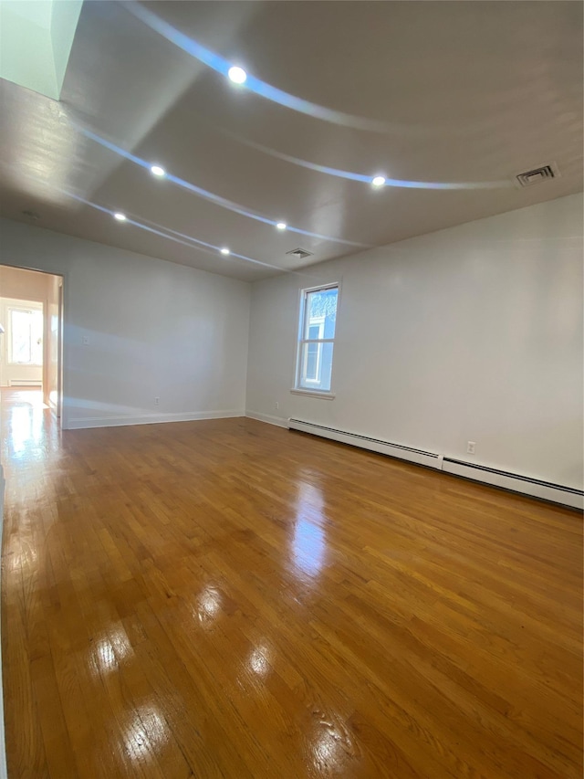 unfurnished room with hardwood / wood-style flooring and baseboard heating