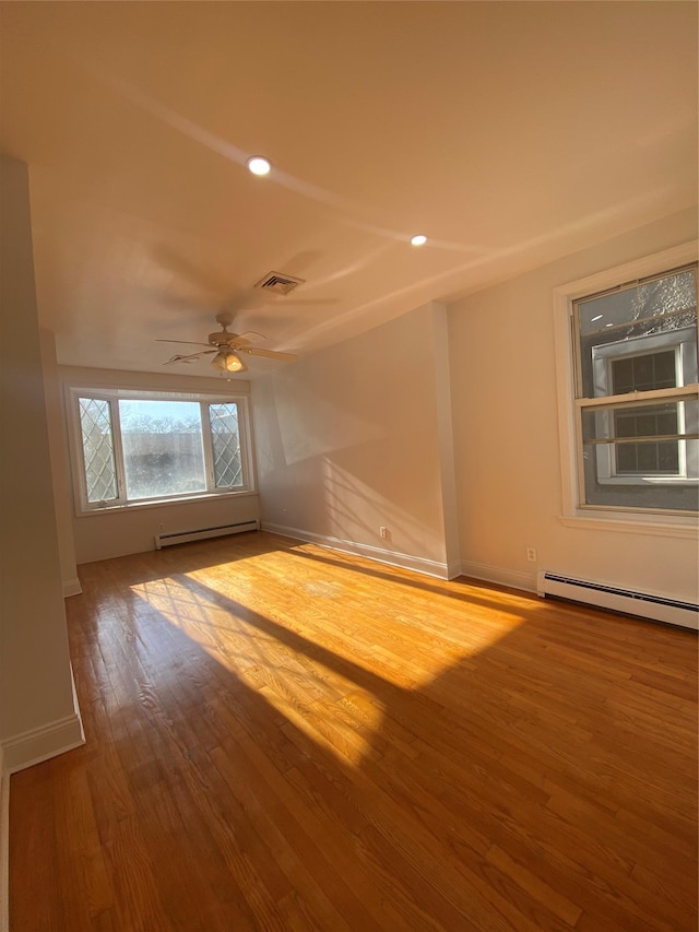 spare room with hardwood / wood-style floors, baseboard heating, and ceiling fan