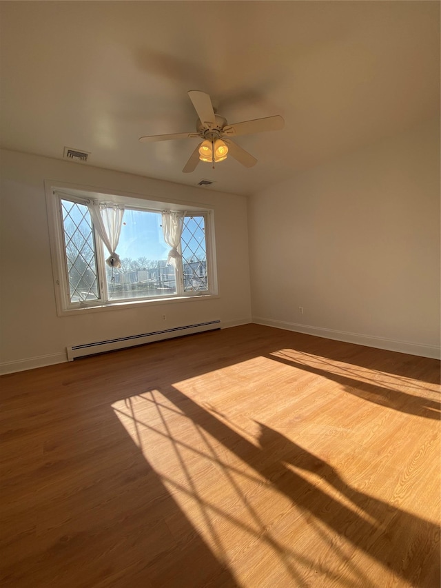 spare room featuring ceiling fan, hardwood / wood-style floors, and a baseboard heating unit