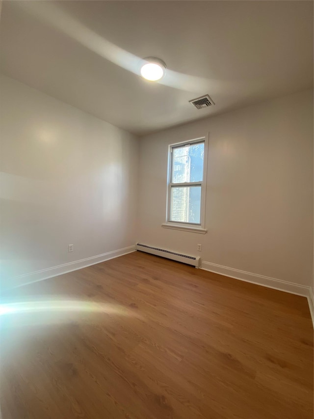 unfurnished room with hardwood / wood-style floors and a baseboard radiator