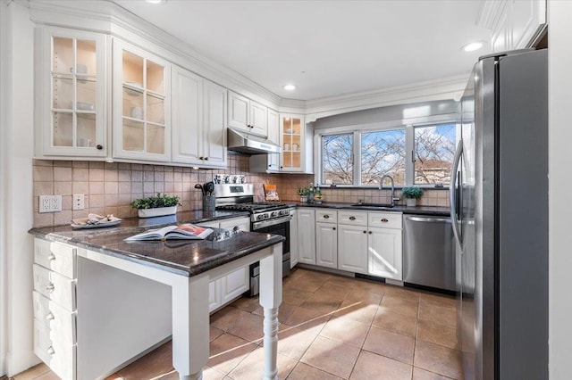 kitchen with decorative backsplash, dark stone counters, stainless steel appliances, sink, and white cabinetry