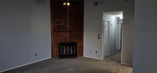 unfurnished living room with a large fireplace, carpet floors, and wooden walls