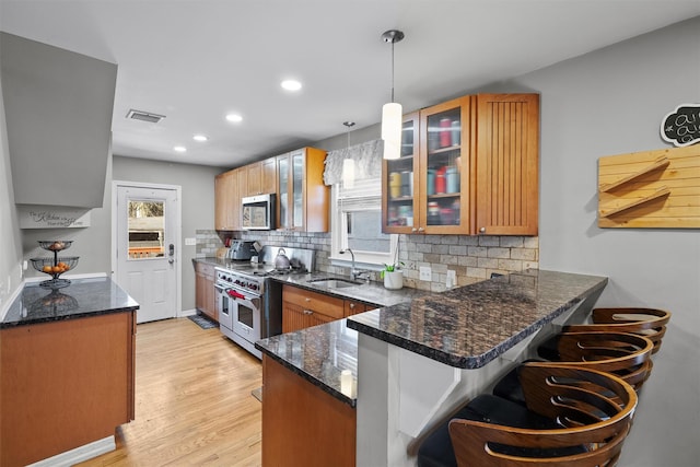 kitchen featuring kitchen peninsula, pendant lighting, a breakfast bar, appliances with stainless steel finishes, and sink