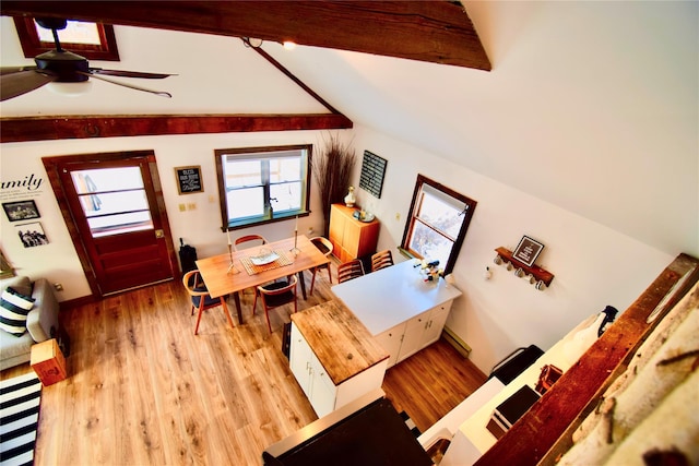 dining space with vaulted ceiling with beams, ceiling fan, and light wood-type flooring