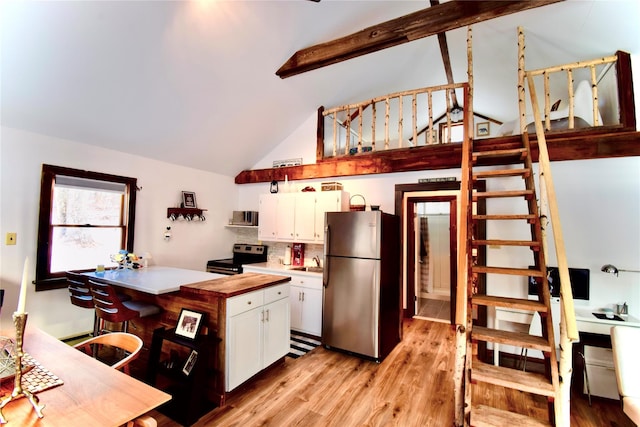 kitchen featuring high vaulted ceiling, white cabinets, sink, light hardwood / wood-style flooring, and appliances with stainless steel finishes