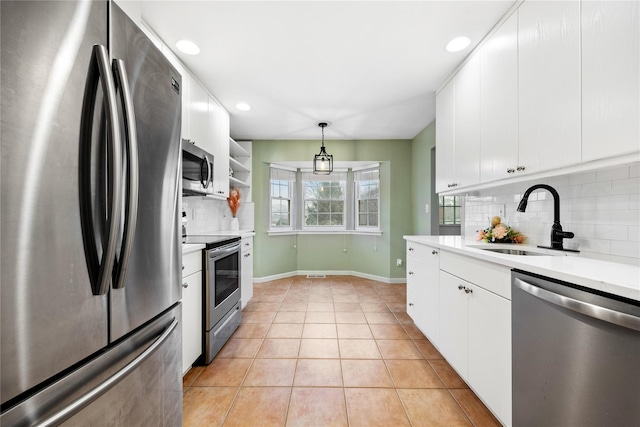 kitchen featuring decorative light fixtures, sink, white cabinetry, and appliances with stainless steel finishes