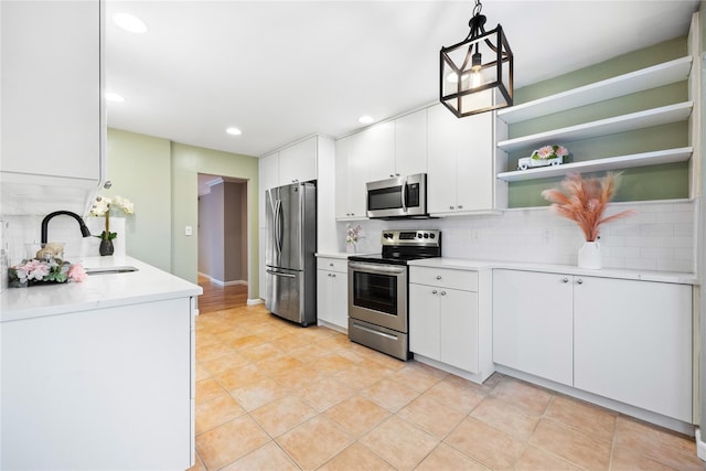 kitchen featuring white cabinetry, sink, pendant lighting, and stainless steel appliances