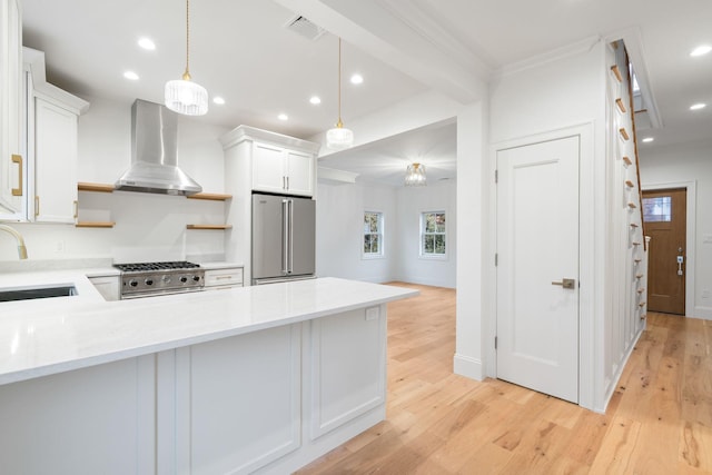 kitchen featuring high end refrigerator, visible vents, light countertops, wall chimney range hood, and a sink