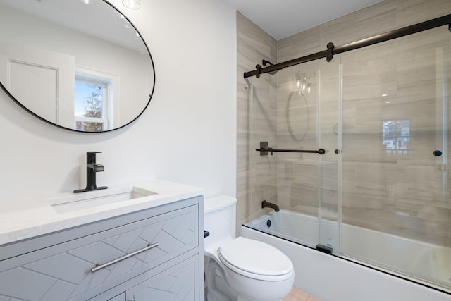 bathroom with shower / bath combination with glass door, vanity, and toilet