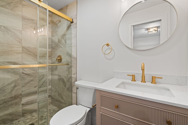 bathroom featuring toilet, a stall shower, and vanity