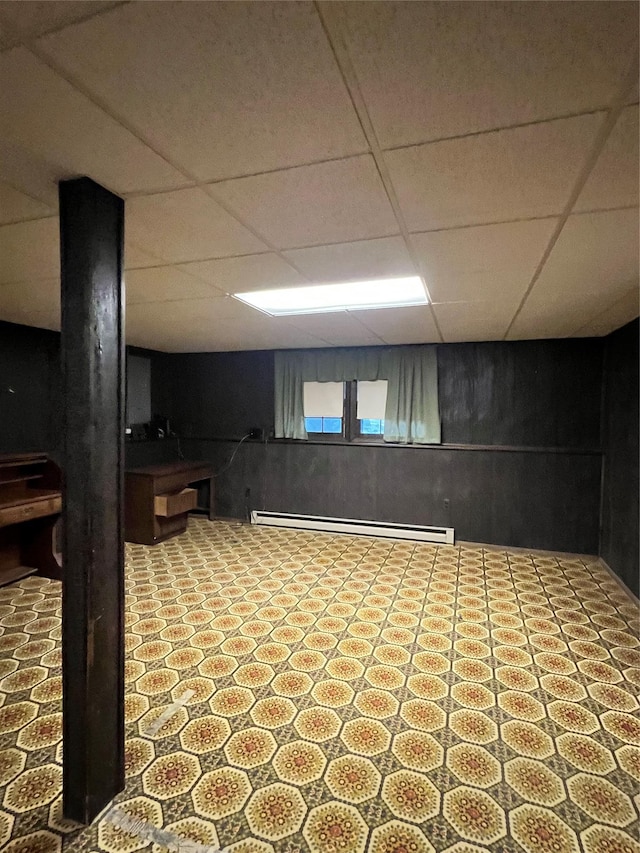 basement featuring a paneled ceiling and a baseboard radiator