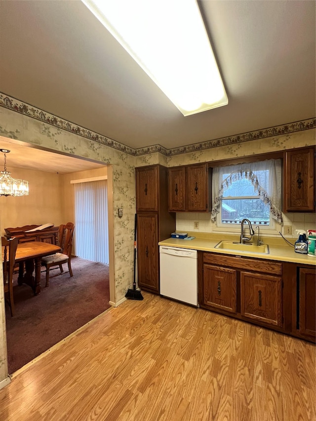 kitchen with dishwasher, light hardwood / wood-style flooring, a notable chandelier, and sink