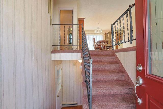 stairway featuring baseboard heating and a notable chandelier