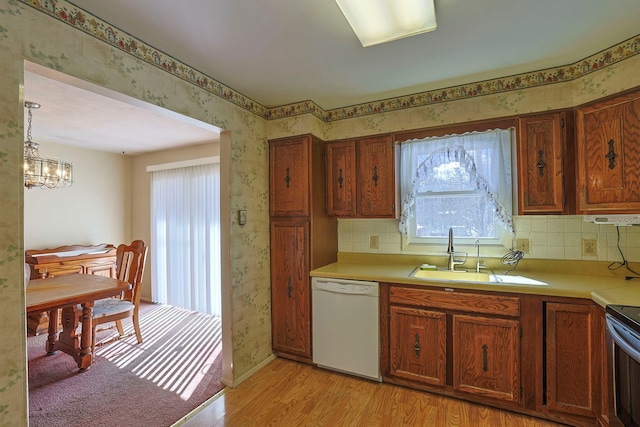 kitchen with light countertops, dishwasher, a sink, and wallpapered walls