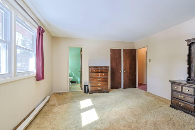 unfurnished bedroom with ensuite bath, carpet, and a baseboard heating unit