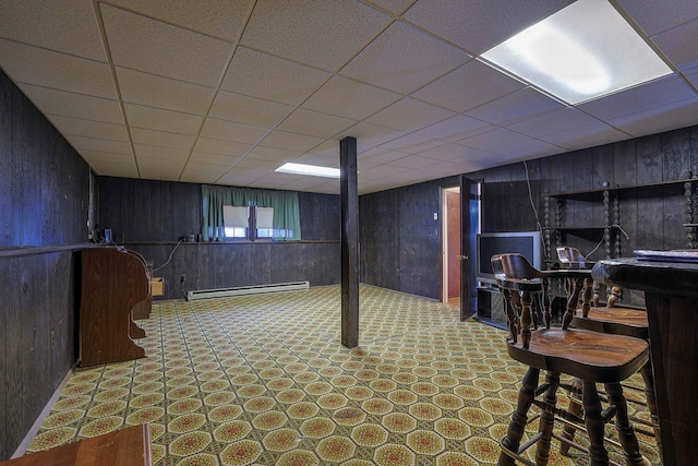 basement with a baseboard heating unit, wooden walls, and tile patterned floors