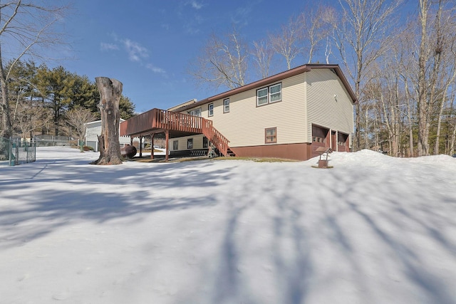 snow covered house featuring stairway and a deck