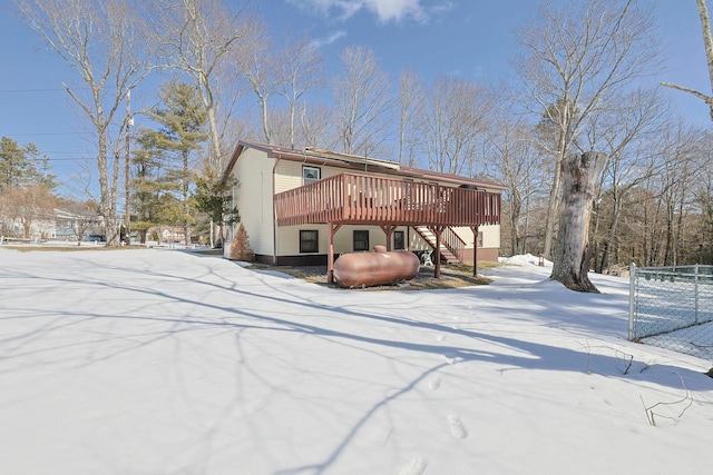 snow covered rear of property featuring a deck, stairway, and fence