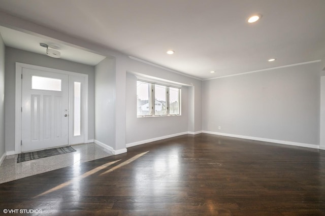 foyer with dark wood-type flooring and crown molding