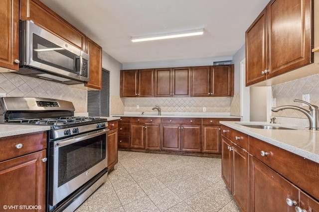 kitchen with light stone countertops, stainless steel appliances, tasteful backsplash, and sink