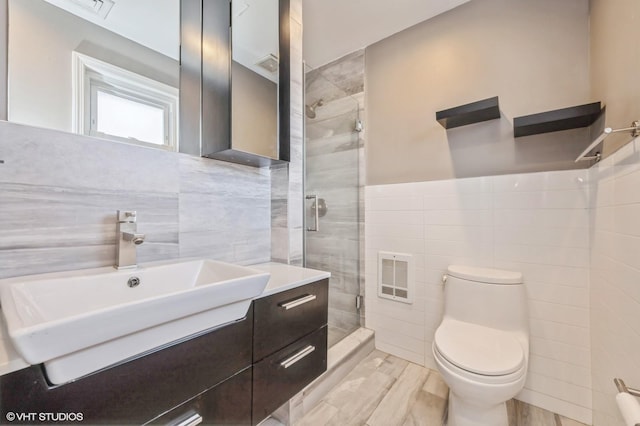 bathroom with an enclosed shower, vanity, toilet, and tile walls