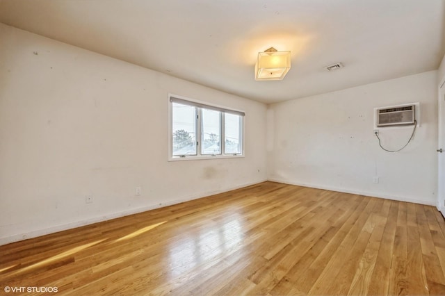 empty room with an AC wall unit and light hardwood / wood-style flooring