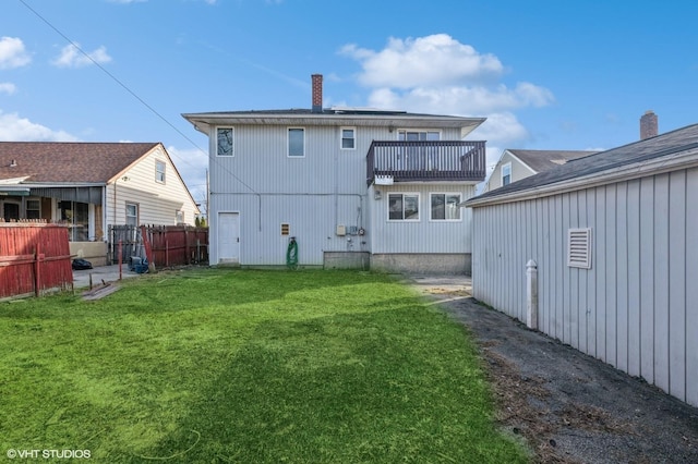 rear view of house with a lawn and a balcony