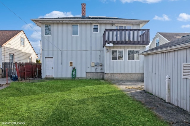 rear view of property with a yard and a balcony