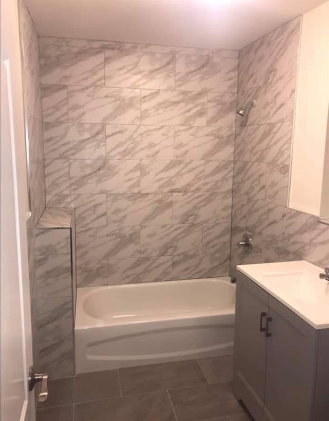 bathroom featuring tile patterned floors, vanity, tiled shower / bath, and tile walls