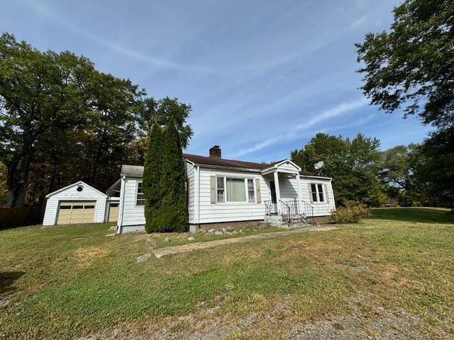 view of front facade featuring a garage, an outdoor structure, and a front lawn