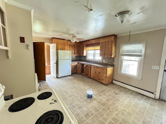 kitchen with backsplash, white appliances, baseboard heating, crown molding, and ceiling fan