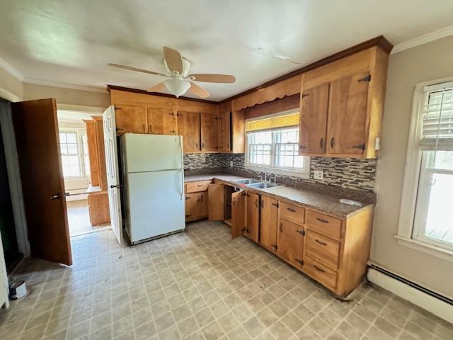 kitchen featuring backsplash, white refrigerator, sink, ceiling fan, and a baseboard radiator