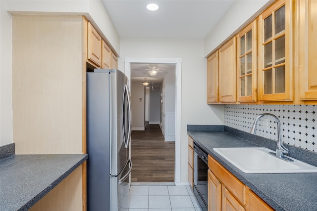 kitchen with sink, black dishwasher, light hardwood / wood-style flooring, backsplash, and stainless steel fridge