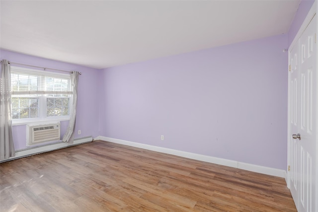 unfurnished room featuring a baseboard radiator, light hardwood / wood-style flooring, and an AC wall unit