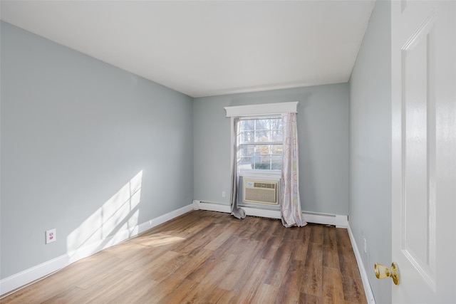 empty room featuring hardwood / wood-style flooring, baseboard heating, and a wall unit AC