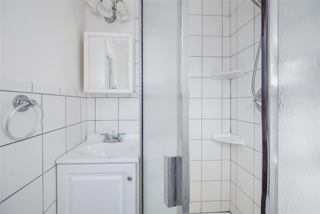 bathroom with vanity, tile walls, and a shower with shower door