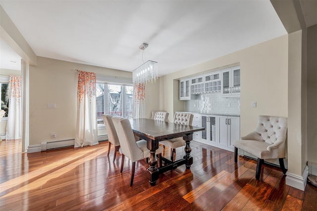 dining space featuring a baseboard radiator, dark hardwood / wood-style flooring, and a notable chandelier