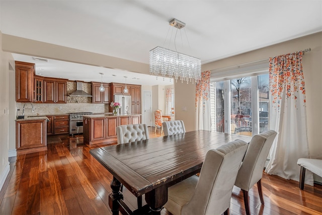 dining space with dark hardwood / wood-style floors, sink, and a notable chandelier