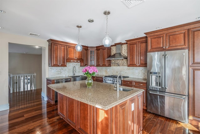 kitchen featuring pendant lighting, sink, stainless steel appliances, light stone counters, and wall chimney exhaust hood