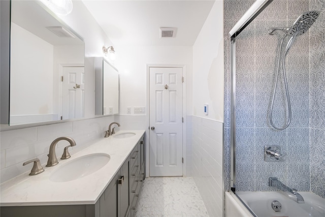 bathroom with shower / bath combination with glass door, tile walls, tile patterned flooring, vanity, and tasteful backsplash