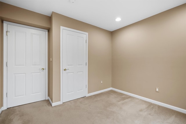 unfurnished bedroom with a closet and light colored carpet