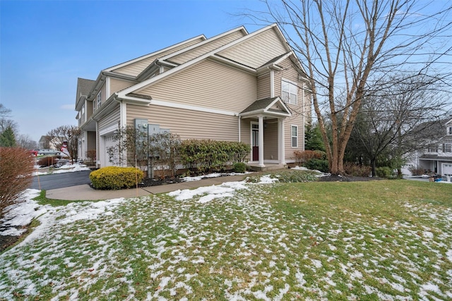 view of snowy exterior featuring a garage and a lawn