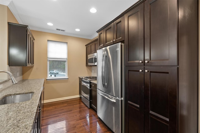 kitchen with visible vents, appliances with stainless steel finishes, ornamental molding, light stone countertops, and a sink